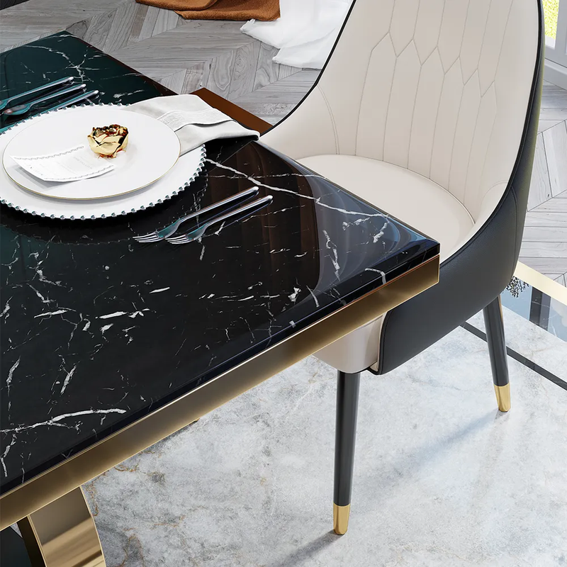 Dining table with black marble top and gold legs, accompanied by a chair.