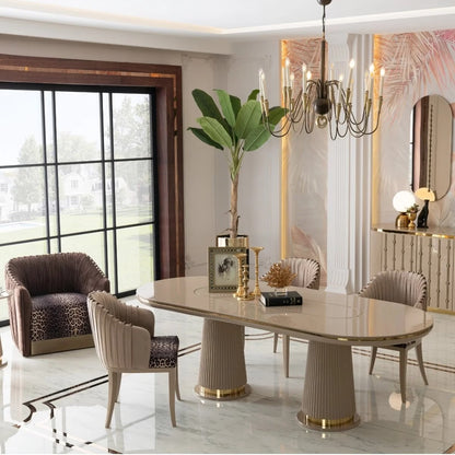 A modern dining room featuring a glossy oval dining table with fluted pedestal legs and matching upholstered chairs, styled in a luxurious interior with a chandelier, large windows, and decorative accents.