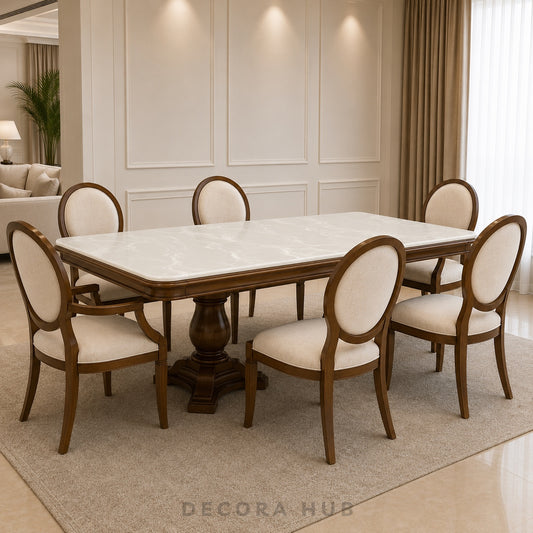 A 6-piece dining set featuring a rectangular table with a white marble-look top and a dark brown wooden pedestal base, surrounded by six matching chairs with cream upholstered seats and backs and dark brown wooden frames, set on a beige rug in a modern dining room.