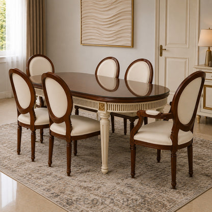 An elegant oval dining table with a glossy dark wood finish and cream-colored pedestal legs, surrounded by six matching high-back chairs with cream upholstered seats and backs, set on a patterned area rug in a classic dining room.