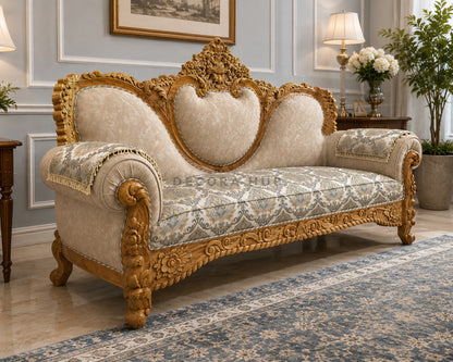Decorative sofa with gold frame and floral patterns in a room with a lamp and plant.