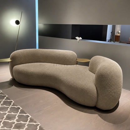 Modern beige sofa in a minimalistic room with a light blue wall and patterned rug.