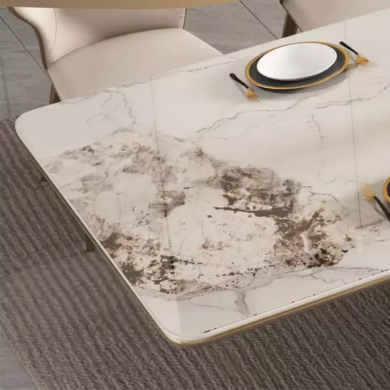 A rectangular dining table with a white marble-look surface featuring gray and brown veining, styled with plates and cutlery in a modern dining room setting.